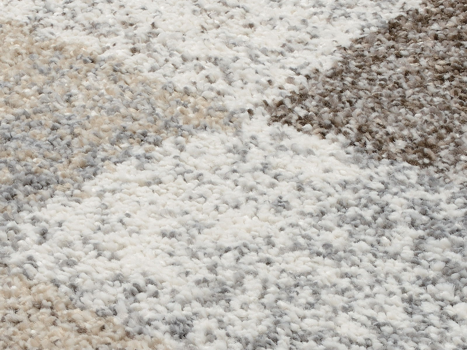 Nahaufnahme eines Frisé-Teppichs mit einem Muster in Beige-, Grau- und Brauntönen. Die Perspektive zeigt die Textur und das Muster des Teppichs aus der Vogelperspektive.
