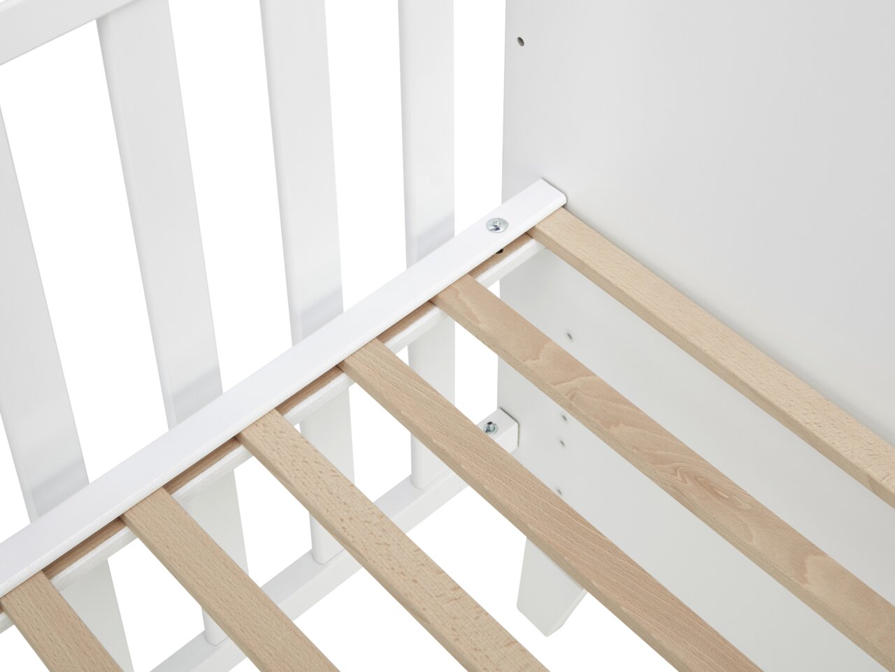 Nahaufnahme eines Babybetts mit weißen Gitterstäben und einem Lattenrost aus hellem Holz, von oben betrachtet.
