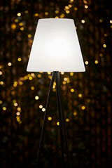 Solar Standleuchte mit dreibeinigem Stativ und weißem Lampenschirm, beleuchtet in einer stimmungsvollen Umgebung, seitliche Perspektive