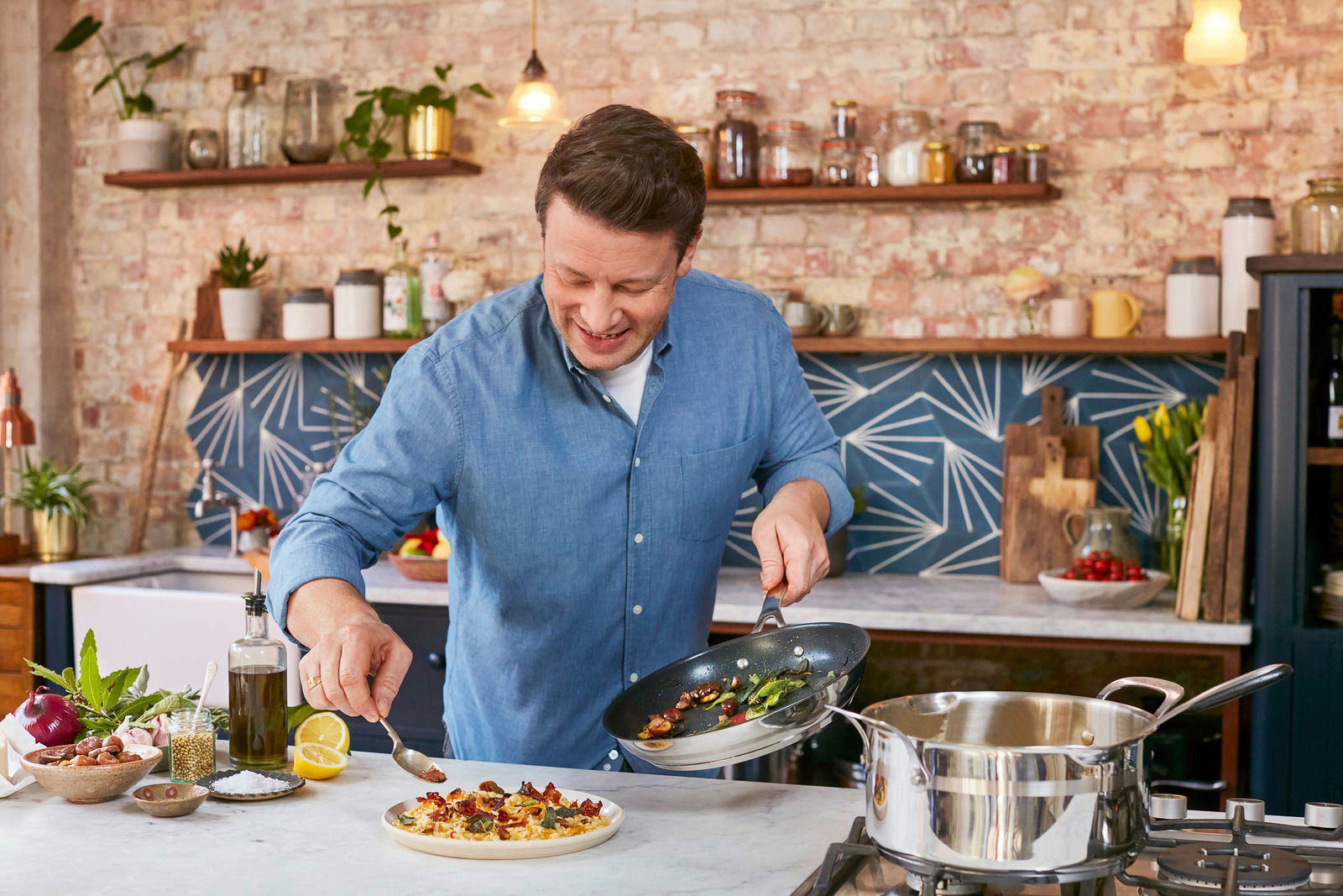 Tefal Bratpfanne 28 cm Jamie Oliver Smart Koch in einer modernen Küche, der eine Bratpfanne hält und ein Gericht anrichtet. Die Perspektive zeigt die Pfanne von oben.