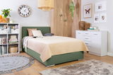 Gemütliches Boxbett 120 in einem modernen Schlafzimmer mit grüner Polsterung, beige Steppdecke und dekorativen Kissen, umgeben von stilvollen Möbeln und Dekorationen. Perspektive von schräg vorne.