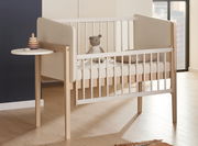 Kinderbett mit seitlichem Tablar, von schräg vorne fotografiert, mit einem Stofftier und einem Stapelspielzeug.