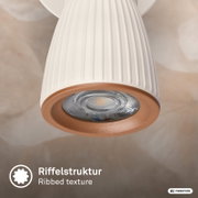 Nahaufnahme einer weißen, geriffelten Pendelleuchte mit kupferfarbenem Lampenring und sichtbarem LED-Spot, von unten im Untersichtwinkel fotografiert