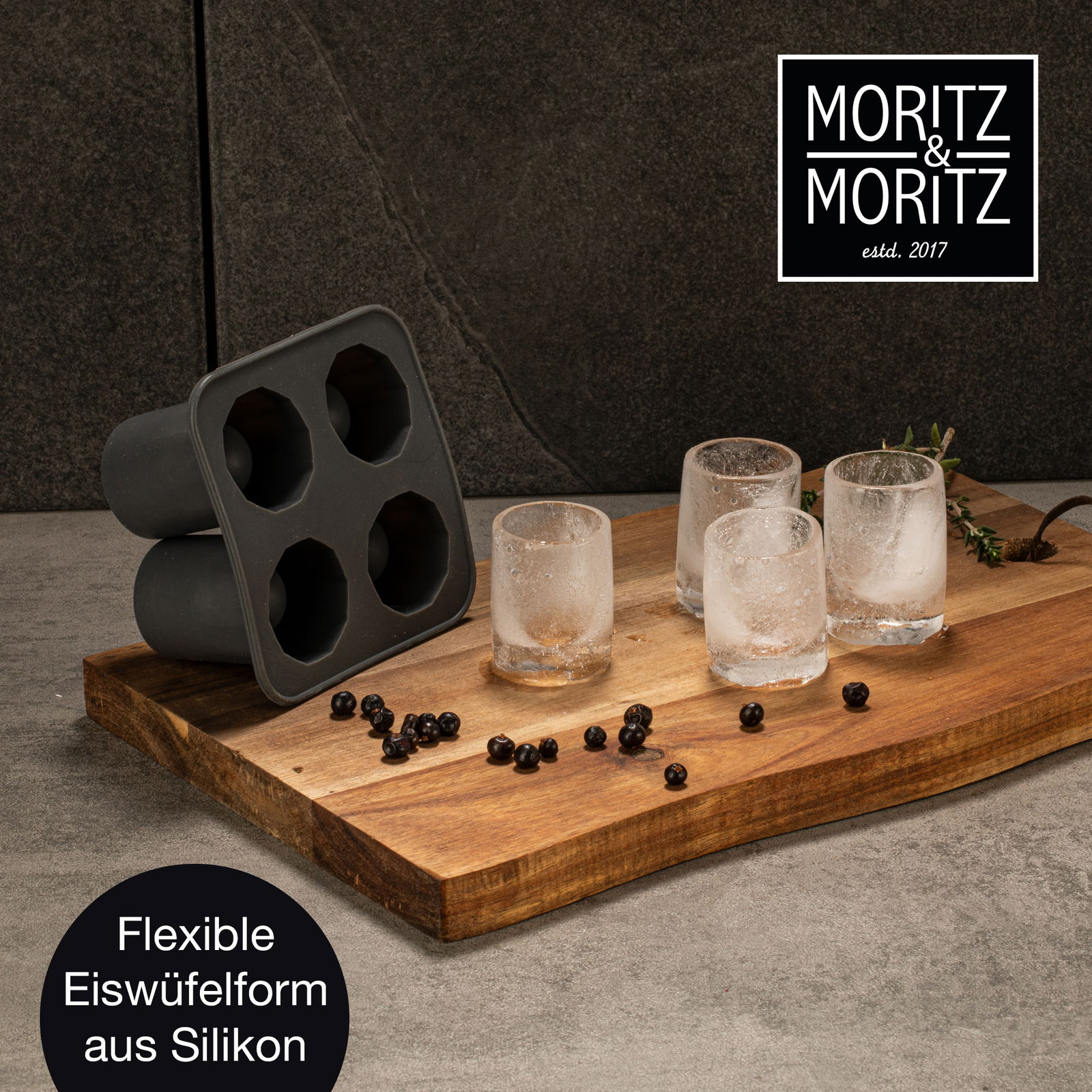 Flexible Eiswürfelform aus Silikon, seitlich auf einem Holzbrett präsentiert, mit vier runden Eiswürfeln daneben.