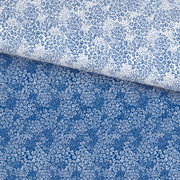 Nahaufnahme von blau-weiß gemusterter Bettwäsche mit kleinen Blumen und Punkten, schräg von oben fotografiert