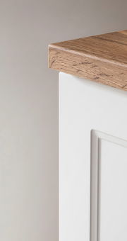 Nahaufnahme eines Unterschranks mit weißer Front und Holzarbeitsplatte, seitliche Perspektive