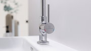 Moderne Waschtischarmatur aus Chrom in seitlicher Perspektive mit Hebelgriff und farbigen Markierungen für heißes und kaltes Wasser.