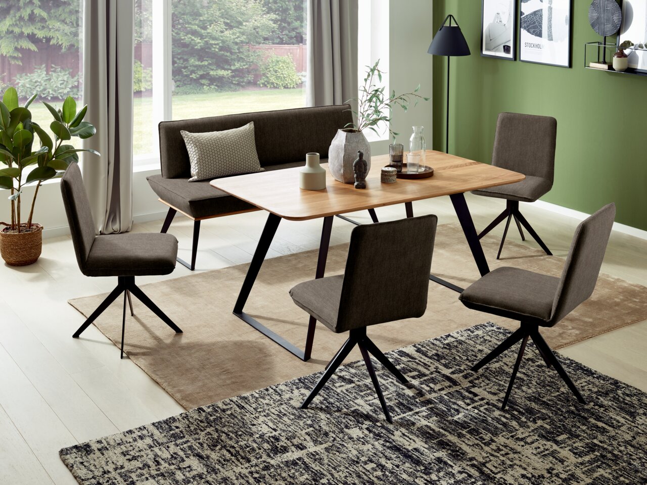 Voleo Bank MALIBU Moderne eethoek met houten tafel en vier gestoffeerde stoelen in een lichte ruimte met grote ramen, zijaanzicht.