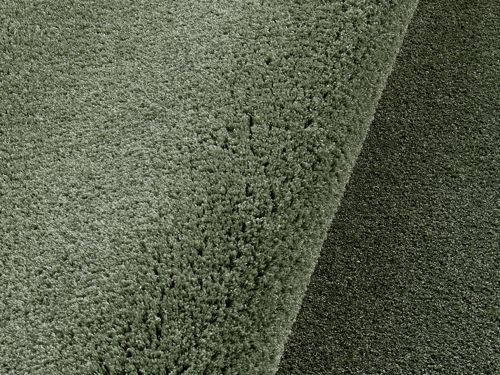 Nahaufnahme eines weichen, runden Teppichs in Grün, perspektivisch von oben fotografiert.