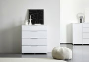 Weiße Schubkastenkommode mit vier Schubladen, frontal fotografiert, dekoriert mit modernen Kerzenhaltern und einem abstrakten Kunstwerk.