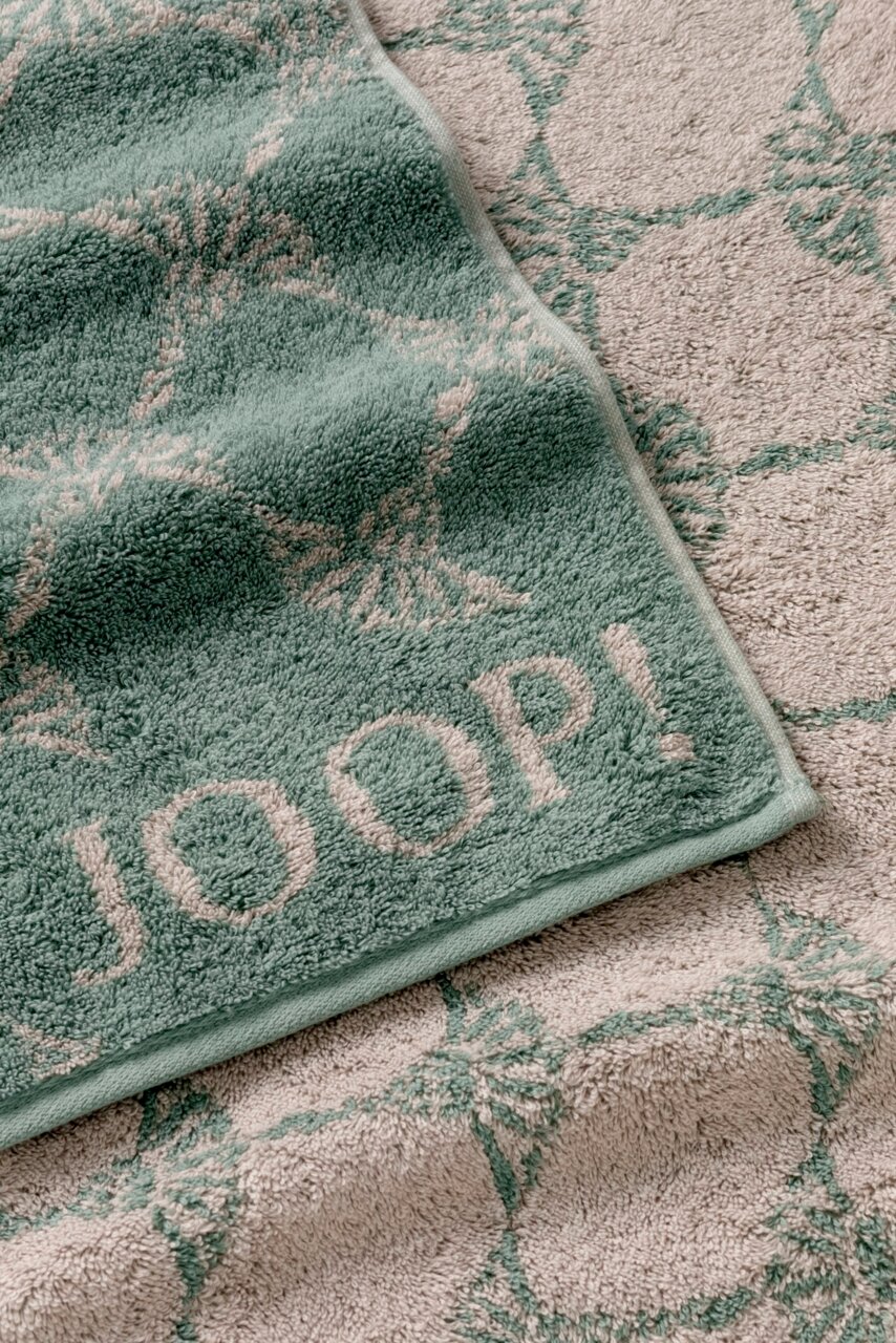 Duschtuch mit grünem und beigem Muster, Markenname JOOP! sichtbar, Perspektive von oben.