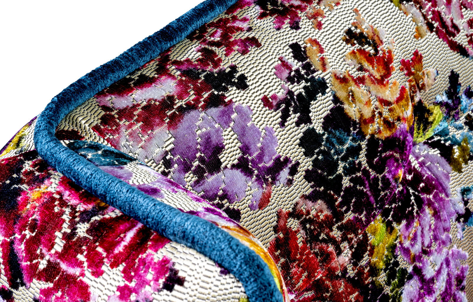 Barnickel Bank FLAIR Nahaufnahme aus schräger Perspektive auf ein dekoratives Kissen mit mehrfarbigem Blumenmuster in Jacquard-Optik und blauem Paspelrand.