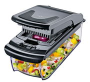 Zwiebel- und Gemüsehacker in seitlicher Perspektive, der bunte Gemüsewürfel in einem transparenten Behälter auffängt.