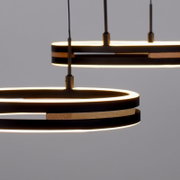 Close-up vanuit zijaanzicht van twee moderne zwarte ronde hanglampen met warmwitte ledverlichting en houten accenten.