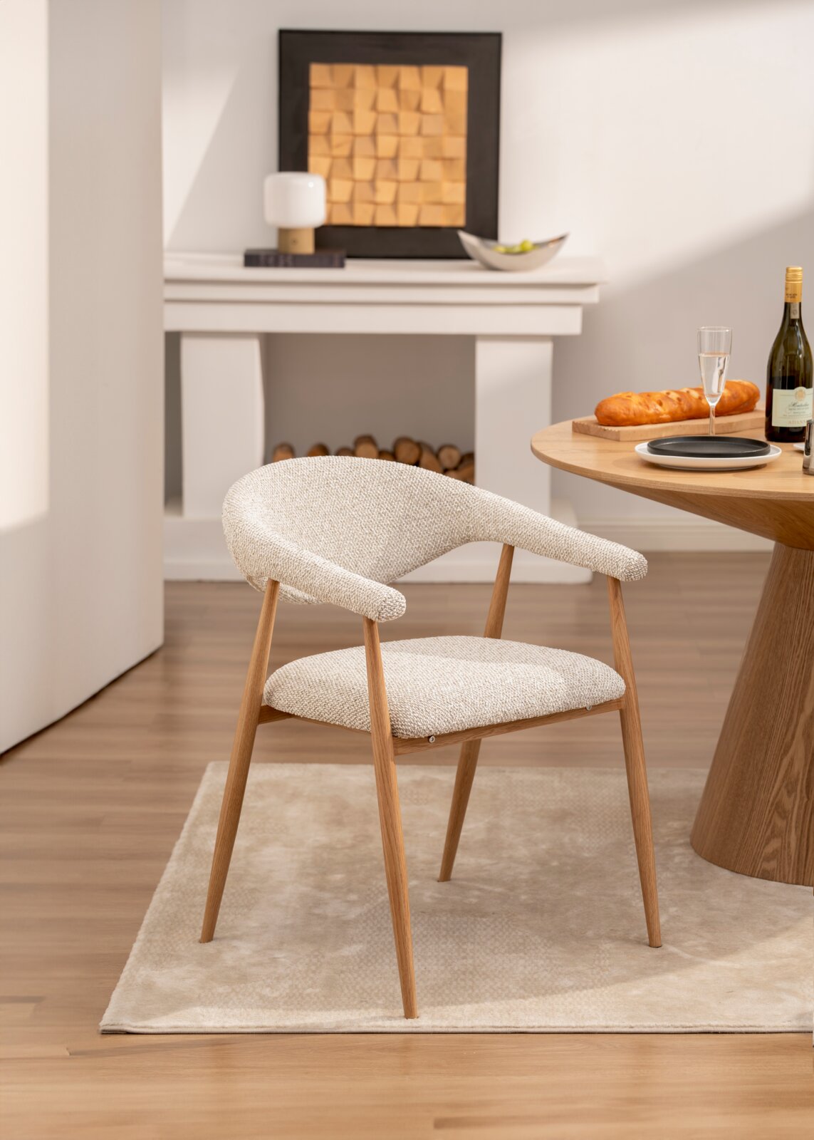 Gepolsterter Esszimmerstuhl mit cremefarbenem Strukturstoff und Holzbeinen, seitliche 3/4-Ansicht in modernem Essbereich neben rundem Holztisch