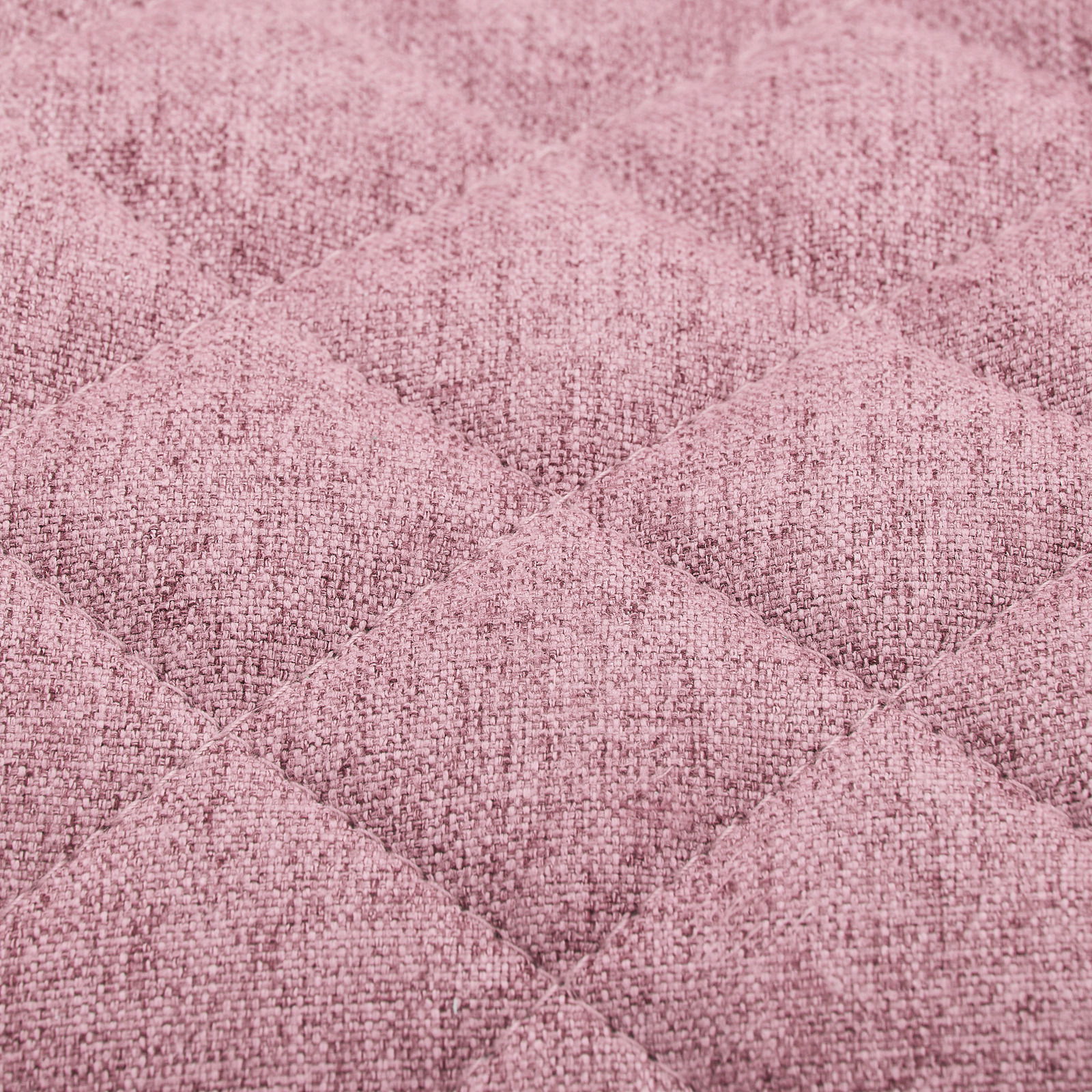 Nahaufnahme eines rosa gepolsterten Stoffes mit gestepptem Rautenmuster, perspektivisch von oben betrachtet.