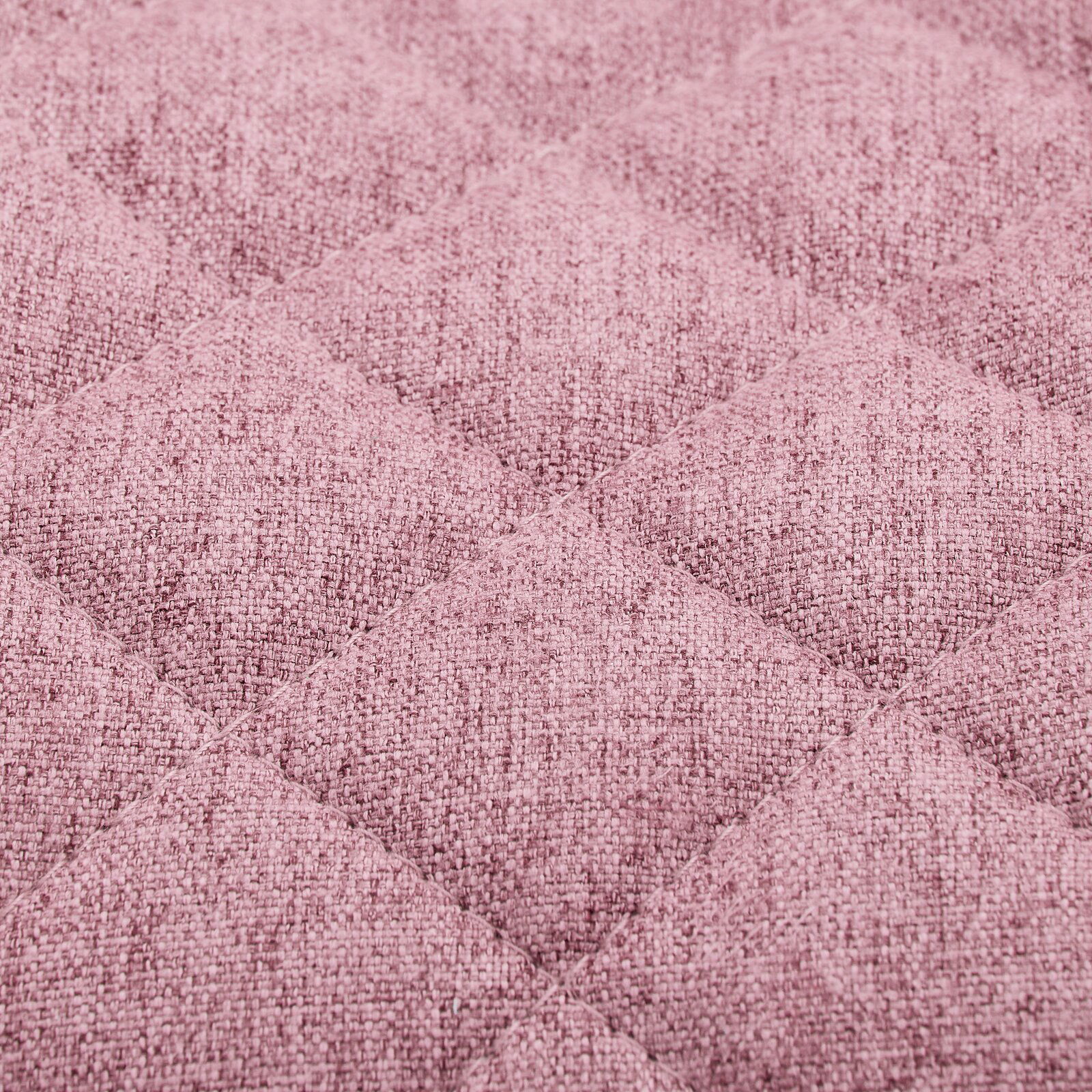 Nahaufnahme eines rosa gepolsterten Stoffes mit gestepptem Rautenmuster, perspektivisch von oben betrachtet.