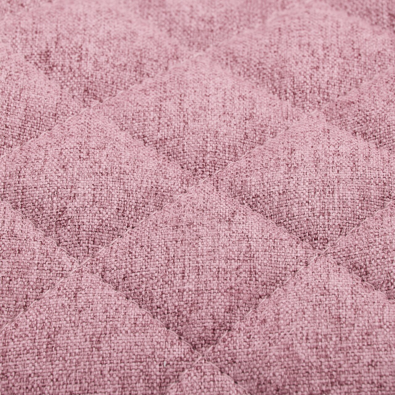 Nahaufnahme eines rosa gepolsterten Stoffes mit gestepptem Rautenmuster, perspektivisch von oben betrachtet.