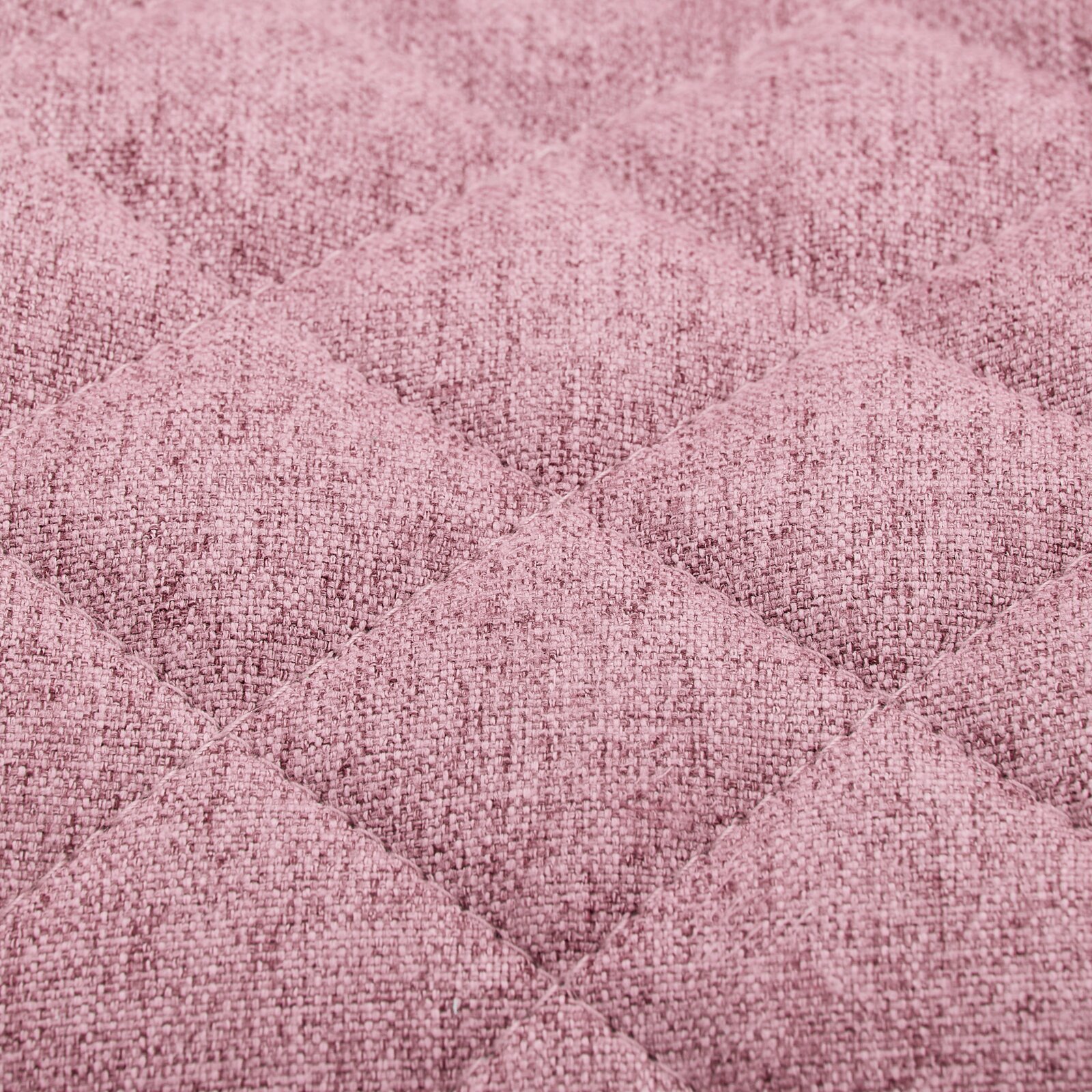 Nahaufnahme eines rosa gepolsterten Stoffes mit gestepptem Rautenmuster, perspektivisch von oben betrachtet.