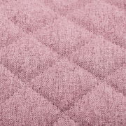Nahaufnahme eines rosa gepolsterten Stoffes mit gestepptem Rautenmuster, perspektivisch von oben betrachtet.