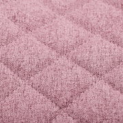 Nahaufnahme eines rosa gepolsterten Stoffes mit gestepptem Rautenmuster, perspektivisch von oben betrachtet.