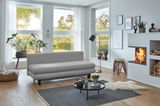 Graues Funktionssofa in modernem Wohnzimmer mit großen Fenstern, Pflanzen und Kamin, seitliche Perspektive.