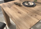 Nahaufnahme eines Esstisches aus hellem Holz mit natürlicher Maserung, dekoriert mit Tellern und Schalen, aus der Perspektive von oben.