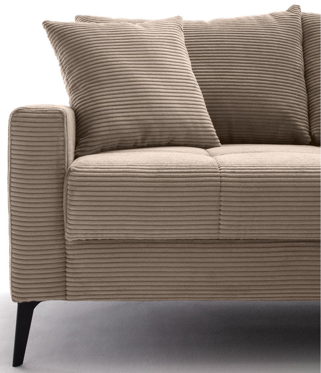 Nahaufnahme einer beigen, gerippten Sofaecke mit zwei passenden Kissen, seitliche Perspektive.