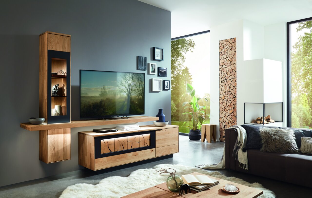 Moderne houten wandcombinatie met tv, planken en decoraties in een stijlvolle woonkamer, gezien vanuit de zijkant.