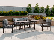 Moderne Gartenmöbel-Set mit einem Tisch und zwei Sesseln auf einer Terrasse, umgeben von grünen Pflanzen, seitliche Perspektive