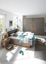 Modernes Schlafzimmer mit Schwebetürenschrank und Bettanlage in heller, freundlicher Atmosphäre. Perspektive von vorne auf das Bett und den Schrank.