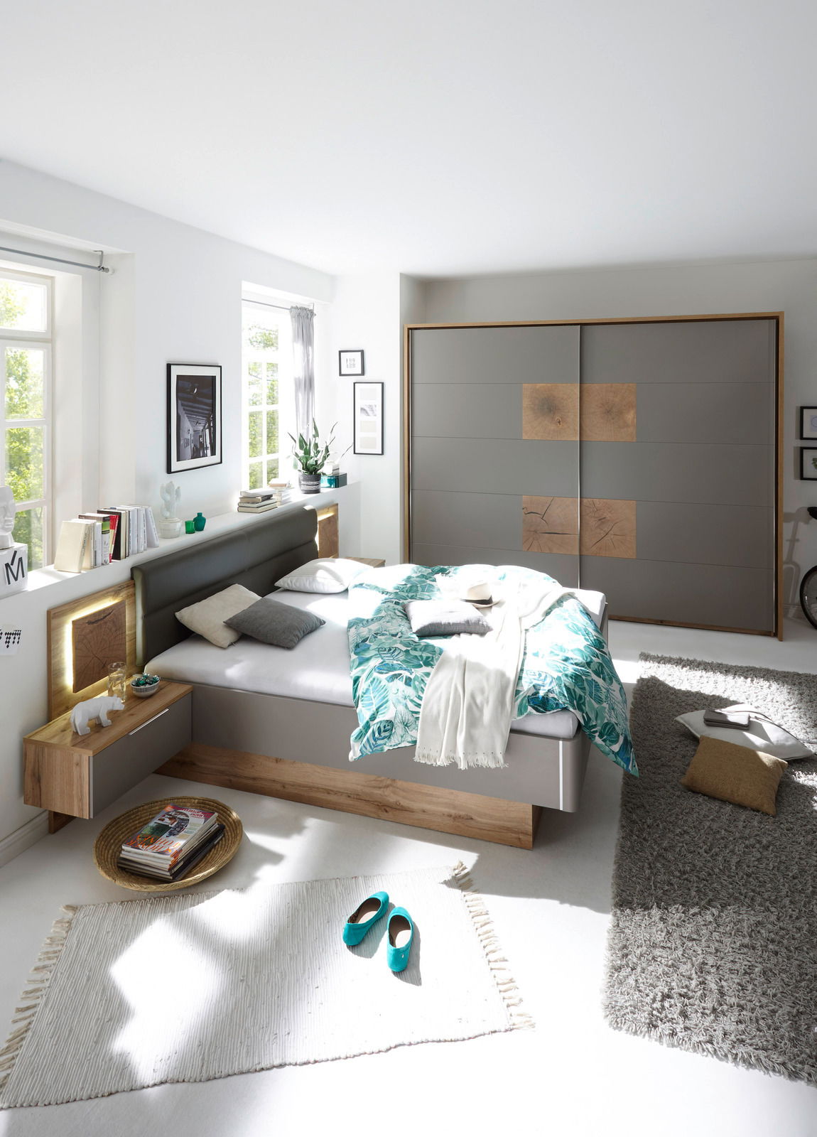 Modernes Schlafzimmer mit Schwebetürenschrank und Bettanlage in heller, freundlicher Atmosphäre. Perspektive von vorne auf das Bett und den Schrank.