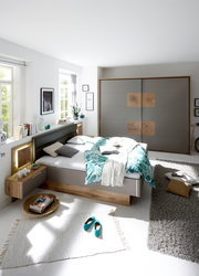 Modernes Schlafzimmer mit Schwebetürenschrank und Bettanlage in heller, freundlicher Atmosphäre. Perspektive von vorne auf das Bett und den Schrank.