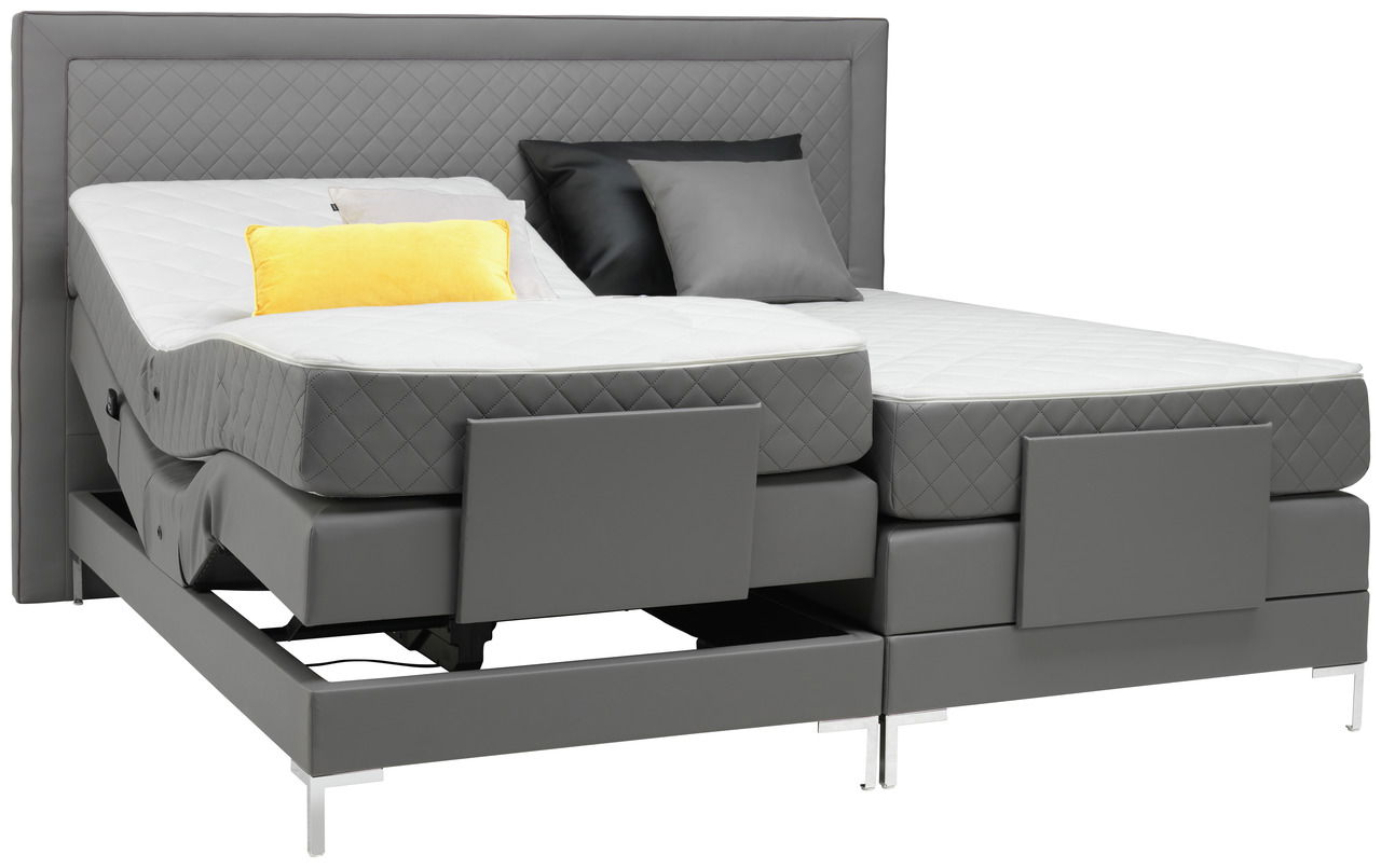 Graues Boxspringbett mit verstellbaren Matratzen, gelbem Kissen und seitlicher Perspektive