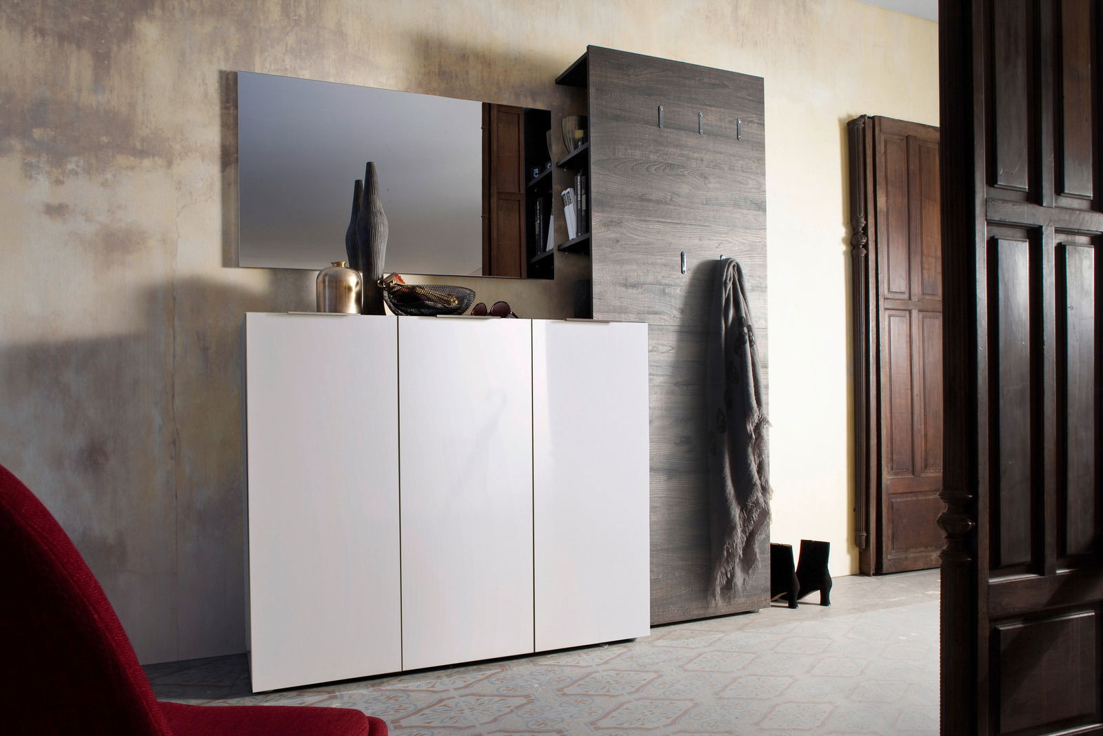 Moderner Eingangsbereich mit weißem Schuhschrank und dunklem Garderobenpaneel, seitliche Perspektive.
