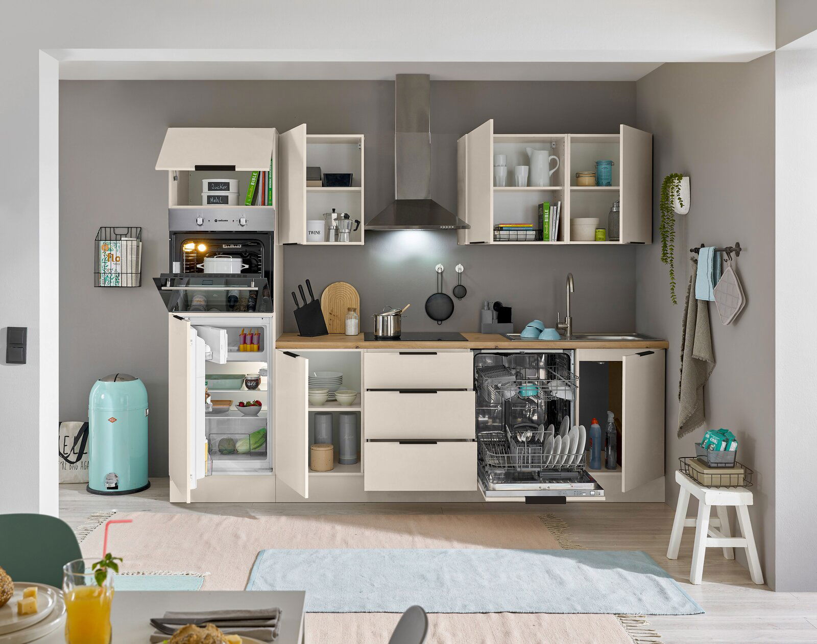 Moderne Küchenzeile mit offenen Schränken, eingebautem Ofen, Kühlschrank und Geschirrspüler, aus frontaler Perspektive.