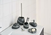 Badezimmer-Set aus grauem Stein mit weißen Streifen, bestehend aus Seifenspender, Zahnbürstenhalter, Becher, Seifenschale und Toilettenbürstenhalter, auf einem weißen Waschbecken von vorne fotografiert.