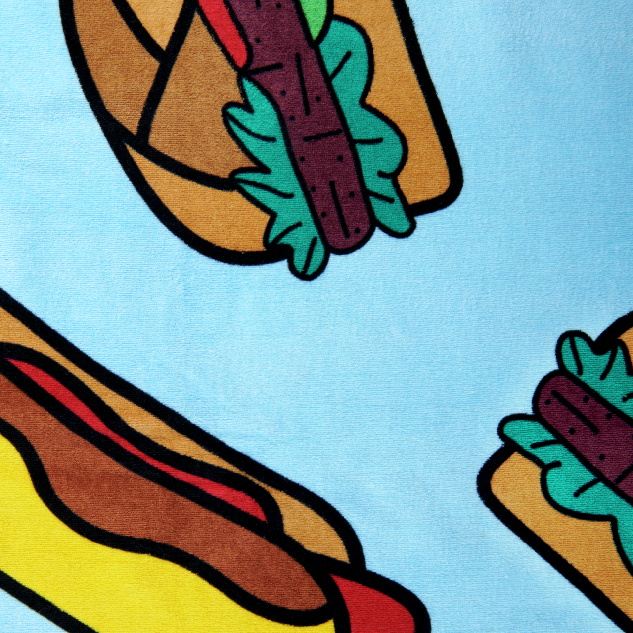 Buntes Velourstuch mit Hotdog-Motiv auf hellblauem Hintergrund, aus der Vogelperspektive fotografiert.