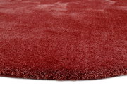 Runder, weicher Teppich in Rot aus der Nähe fotografiert, zeigt die flauschige Textur.