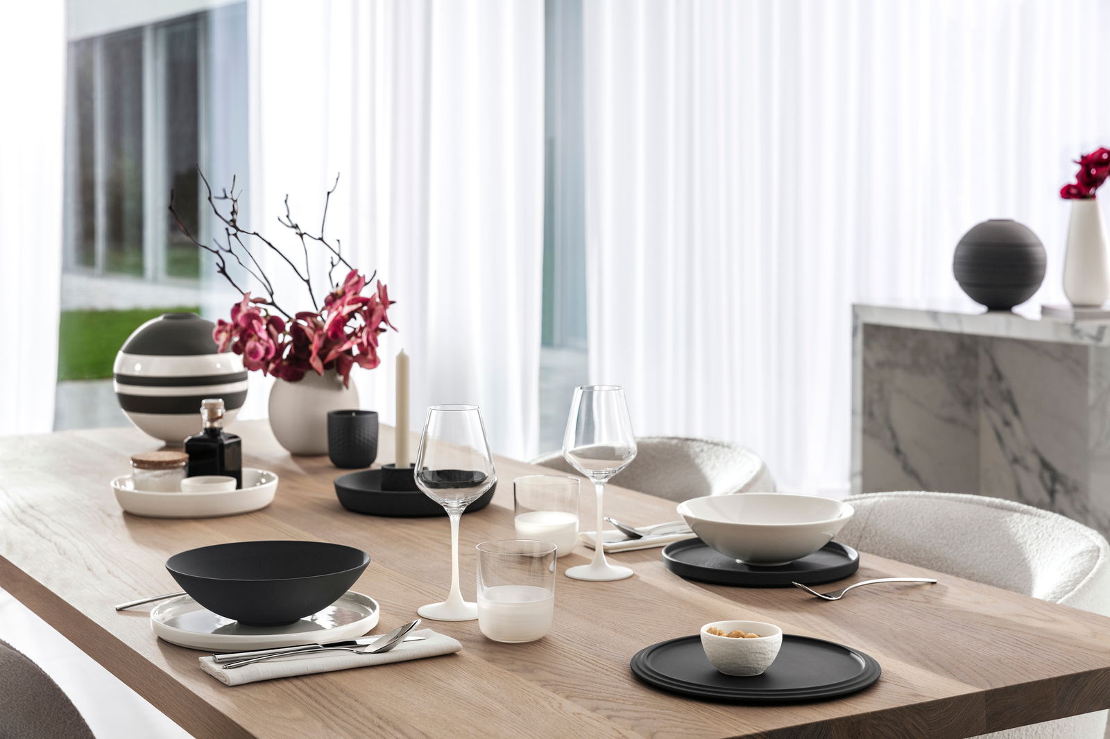 Villeroy & Boch Whiskybecher 4-tlg. Eleganter Esstisch mit modernem Geschirrset, darunter Whisky Tumbler, in einem stilvollen, hellen Raum mit Blick auf den Garten.