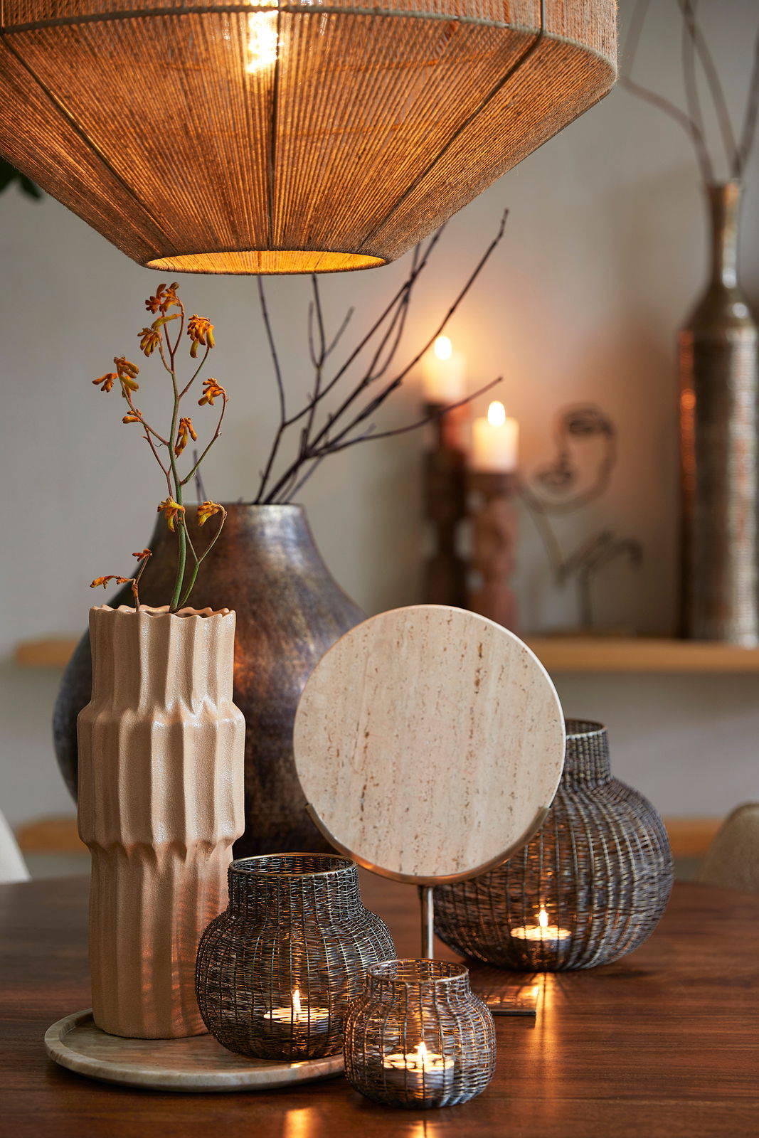 Stimmungsvolle Wohnzimmerszene mit hängender Lampe, dekorativen Vasen und Kerzenhaltern auf einem Holztisch, aus der Perspektive von vorne.