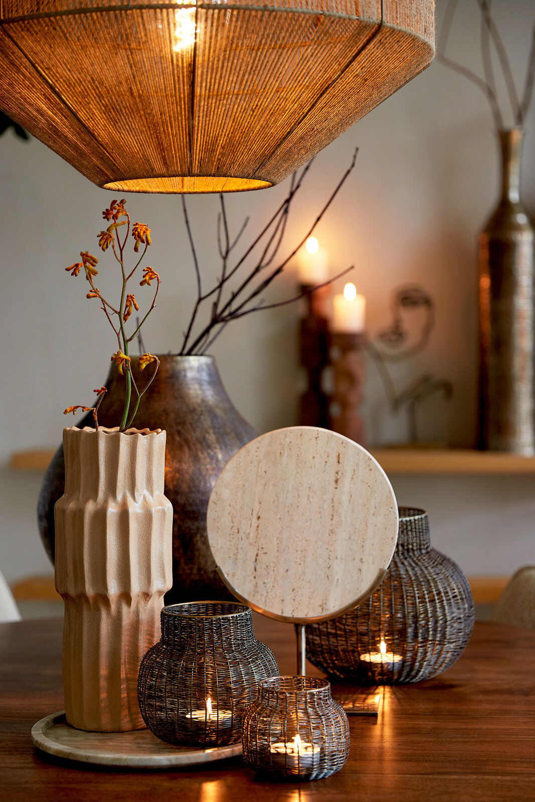 Light&Living Ornament MORENO Stimmungsvolle Wohnzimmerszene mit hängender Lampe, dekorativen Vasen und Kerzenhaltern auf einem Holztisch, aus der Perspektive von vorne.