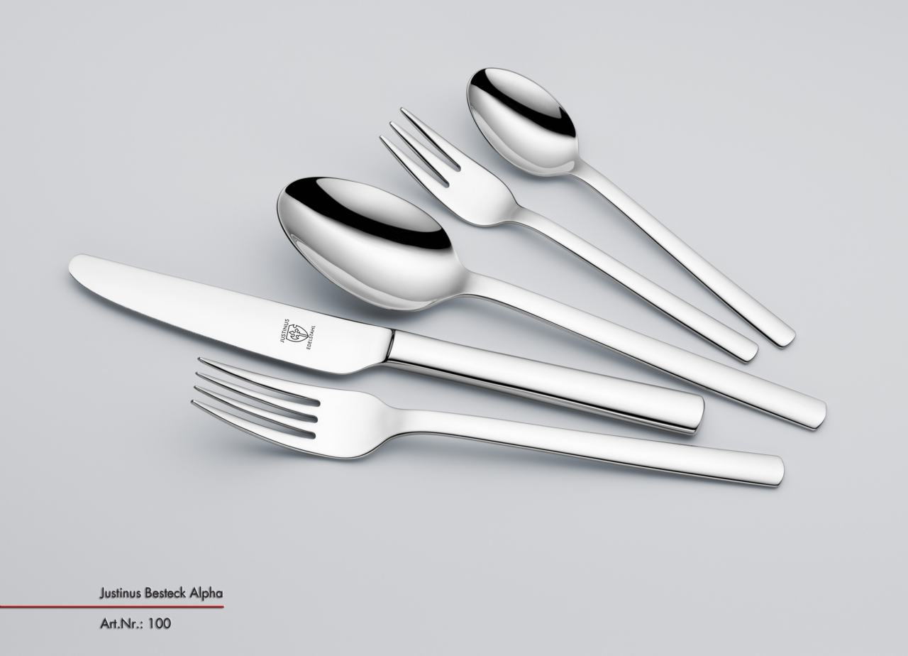 Set aus glänzendem Edelstahlbesteck, bestehend aus Messer, Gabel, Löffel, Dessertgabel und Teelöffel, in schräger Draufsicht.