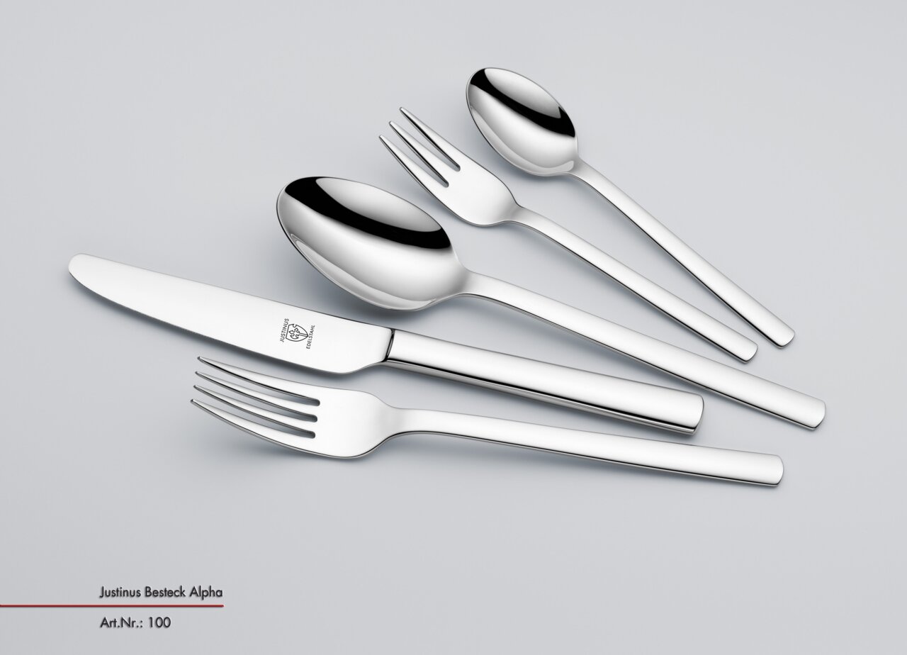 Set aus glänzendem Edelstahlbesteck, bestehend aus Messer, Gabel, Löffel, Dessertgabel und Teelöffel, in schräger Draufsicht.