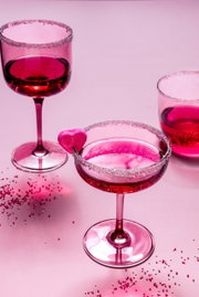 Zwei rosafarbene Weinkelche mit Zuckerrand und Herzdekoration, aus der Vogelperspektive fotografiert.