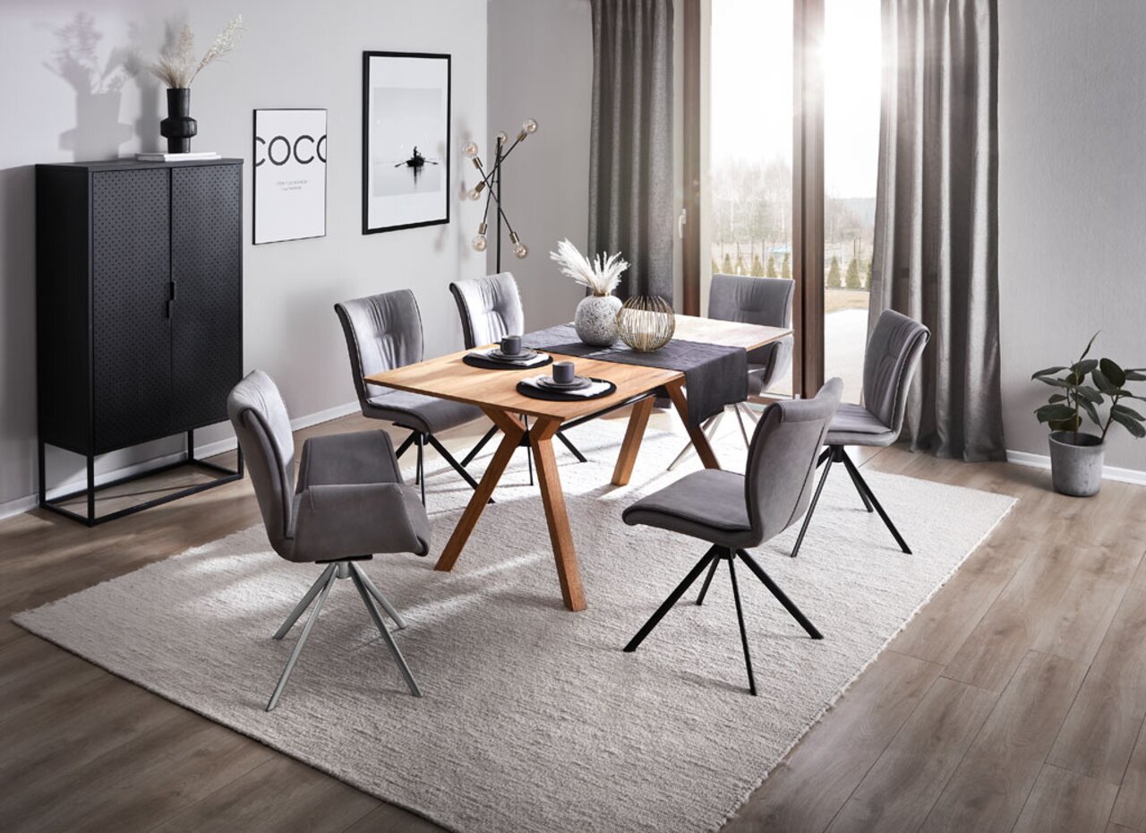 Moderner Esstisch mit Holzplatte und schwarzen Stühlen in einem stilvoll eingerichteten Esszimmer, seitliche Perspektive.