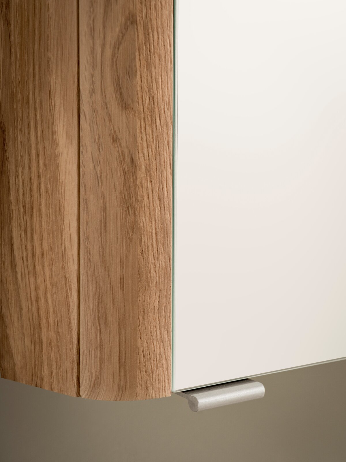 Detailansicht aus schräger Frontperspektive: moderne Möbel- bzw. Schrankfront mit Holzseiten in natürlicher Maserung, weißer Tür/Front und silbernem Griff