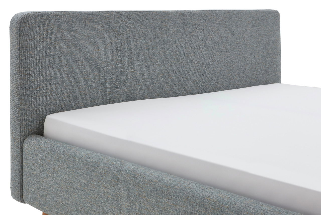 Seitliche Ansicht eines grauen Polsterbettgestells mit Kopfteil.