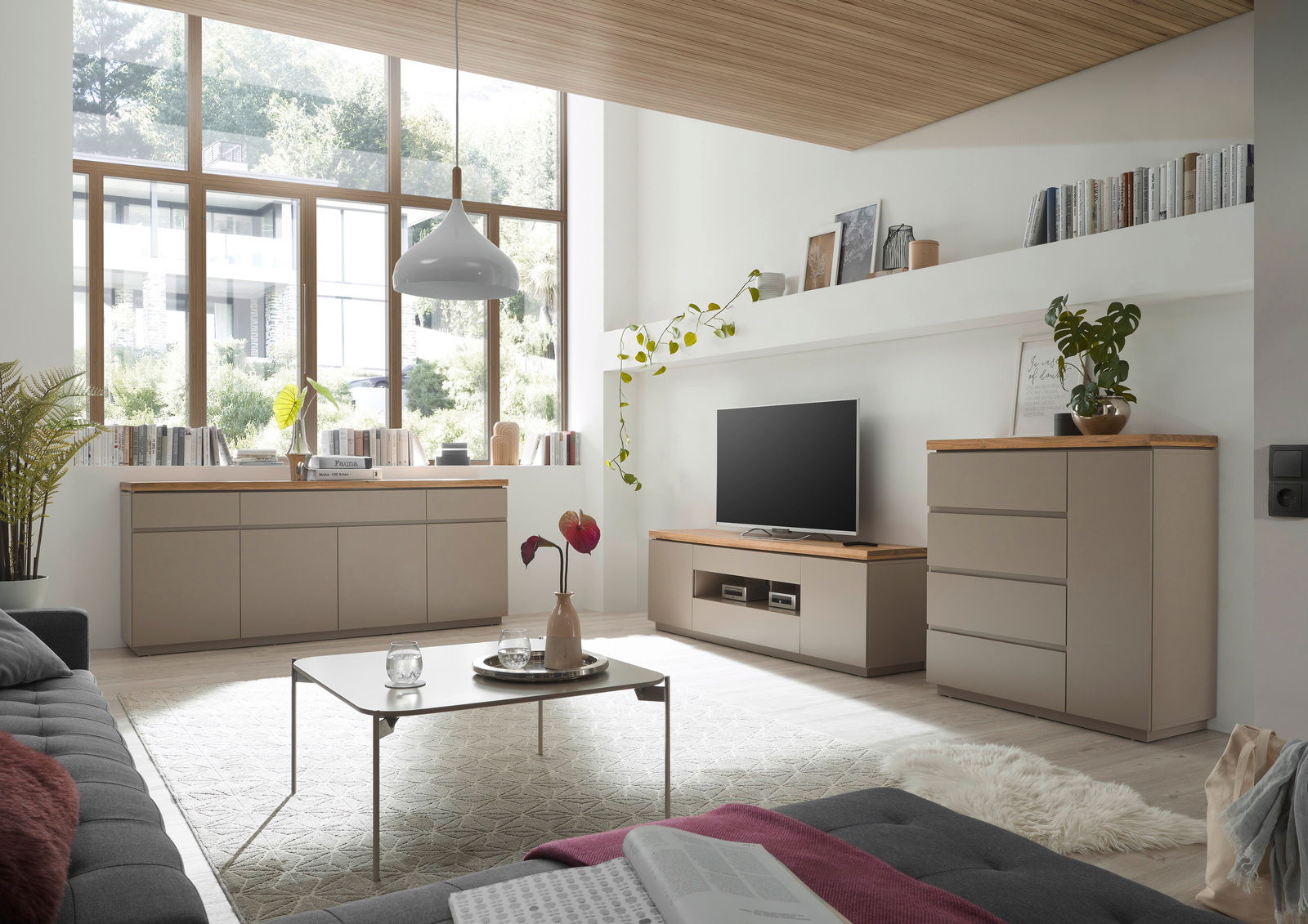 Modernes Wohnzimmer mit TV-Lowboard, Sideboard und Kommode in hellem Holz und neutralen Farben, seitliche Perspektive