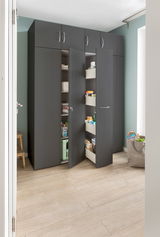 Moderner Apothekerschrank in dunklem Design mit geöffneten Türen, gefüllt mit Haushaltsartikeln, aus der Perspektive eines hellen Raumes betrachtet.